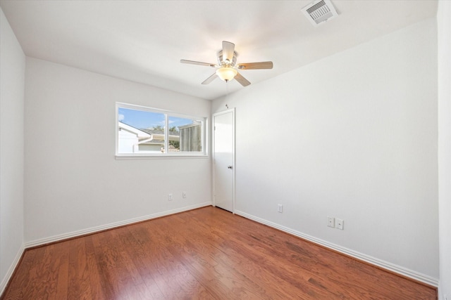 unfurnished room with a ceiling fan, visible vents, baseboards, and wood finished floors