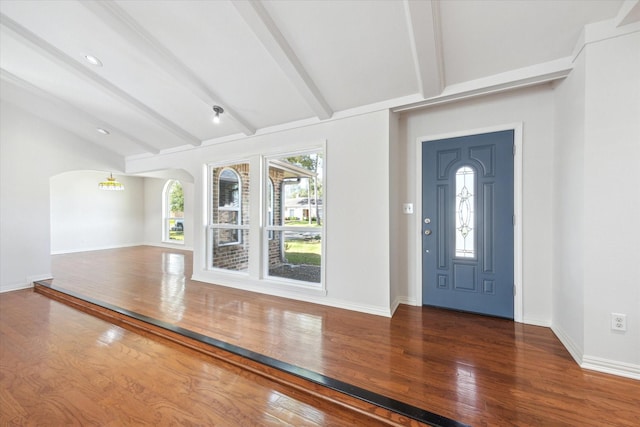 entryway with arched walkways, a healthy amount of sunlight, vaulted ceiling with beams, and wood finished floors