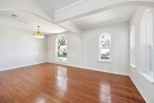 empty room featuring visible vents, baseboards, and hardwood / wood-style flooring