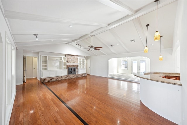 unfurnished living room featuring vaulted ceiling with beams, a fireplace, visible vents, a ceiling fan, and wood finished floors