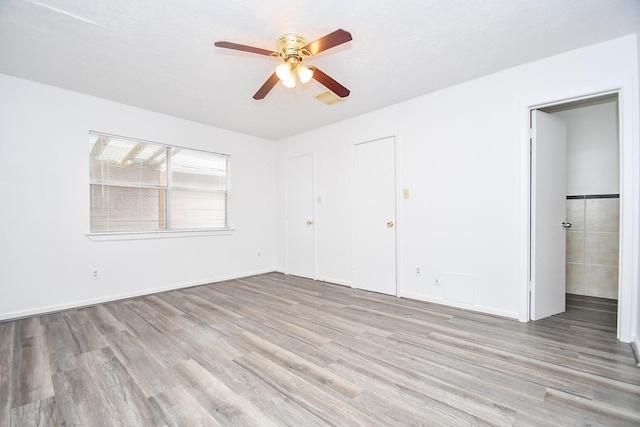 unfurnished bedroom with wood finished floors, visible vents, and a ceiling fan