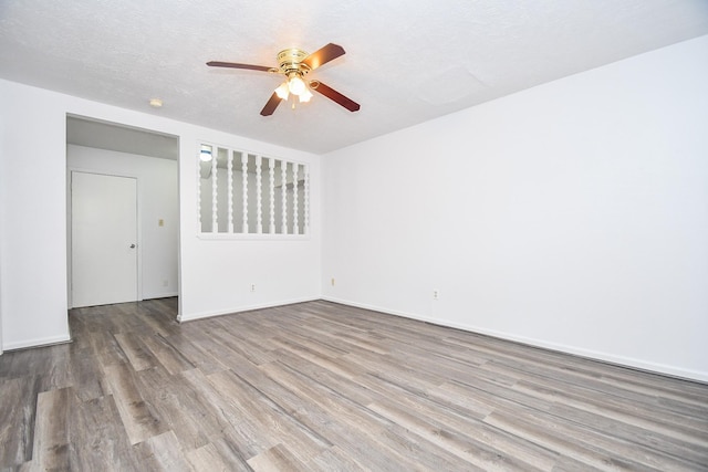 spare room with a ceiling fan, a textured ceiling, baseboards, and wood finished floors