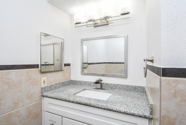 bathroom featuring vanity and tile walls