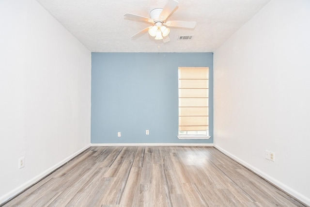 empty room with baseboards, visible vents, a ceiling fan, wood finished floors, and a textured ceiling