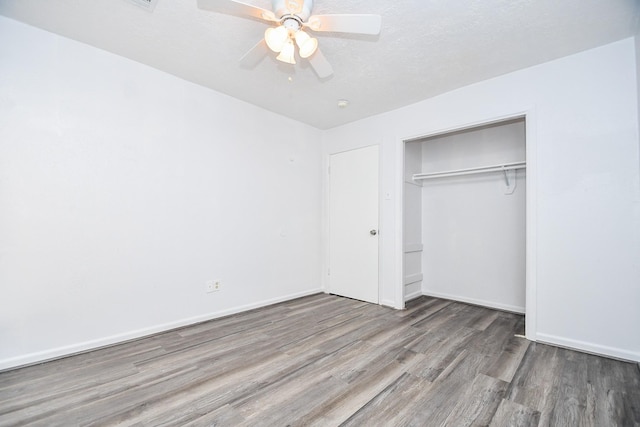 unfurnished bedroom featuring a closet, ceiling fan, a textured ceiling, wood finished floors, and baseboards