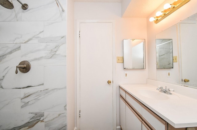 bathroom featuring a marble finish shower and vanity