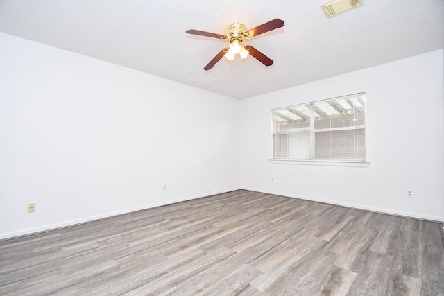 unfurnished room with visible vents, ceiling fan, baseboards, and wood finished floors