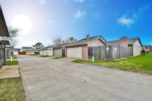 view of front of house with a garage, a front yard, fence, and a residential view