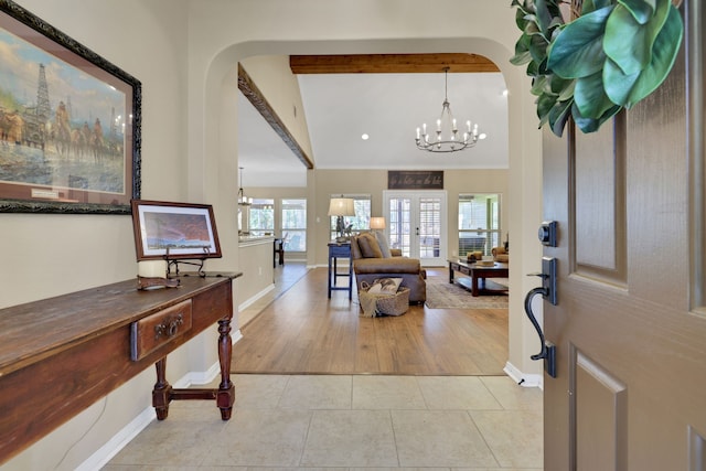 entryway with a chandelier, arched walkways, french doors, and light tile patterned flooring