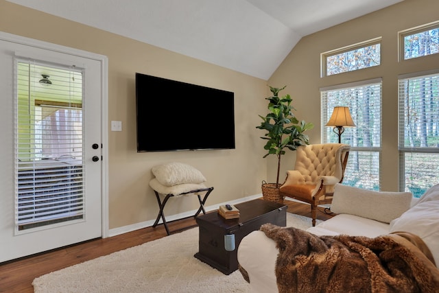 living area featuring baseboards, vaulted ceiling, and wood finished floors