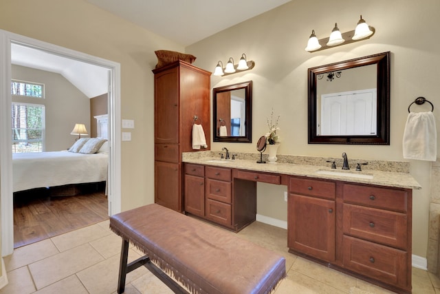 ensuite bathroom with ensuite bathroom, double vanity, a sink, and tile patterned floors