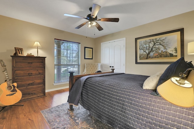 bedroom with a closet, ceiling fan, baseboards, and wood finished floors