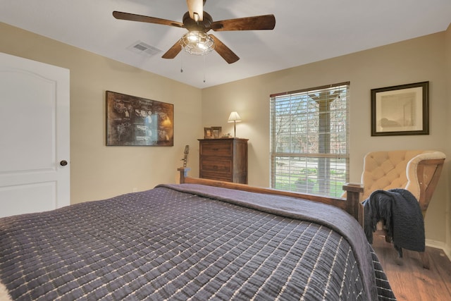 bedroom featuring ceiling fan, visible vents, and wood finished floors