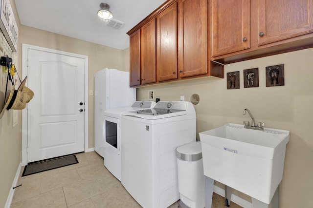 laundry area featuring light tile patterned flooring, a sink, visible vents, independent washer and dryer, and cabinet space