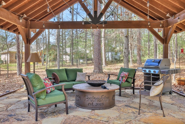 view of patio with an outdoor living space with a fire pit, fence, and area for grilling