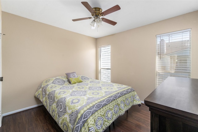 bedroom with ceiling fan, dark wood-type flooring, and baseboards