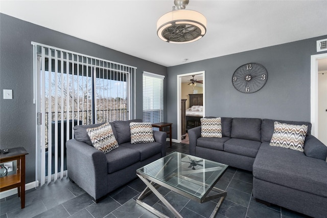 living room with visible vents, ceiling fan, dark tile patterned floors, and baseboards