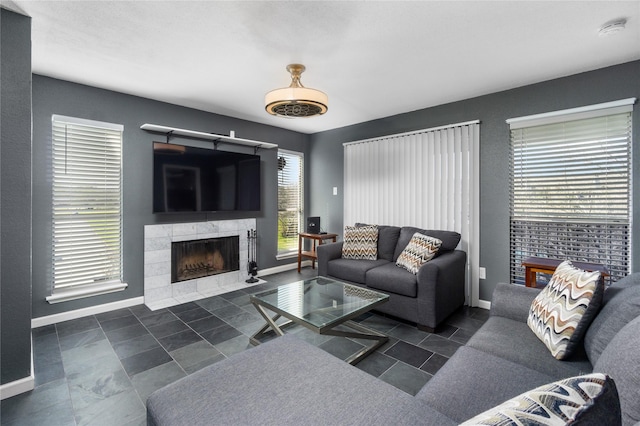 living room with a tile fireplace and baseboards