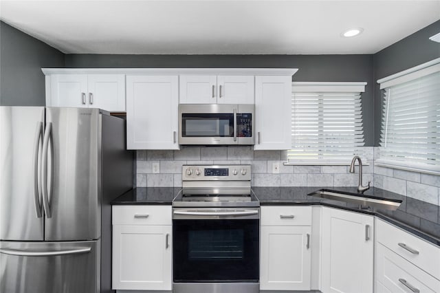 kitchen featuring dark countertops, white cabinetry, appliances with stainless steel finishes, and a sink