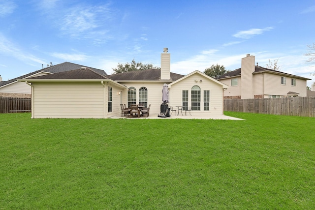 back of property with a patio area, a chimney, fence, and a yard