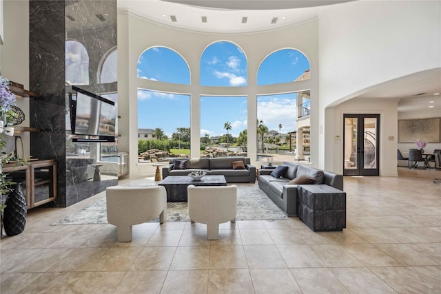 tiled living area with arched walkways, crown molding, and a towering ceiling