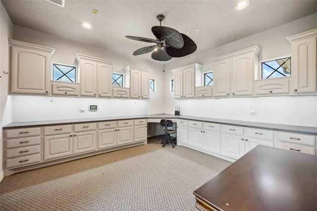 interior space with built in desk, a ceiling fan, light colored carpet, and recessed lighting