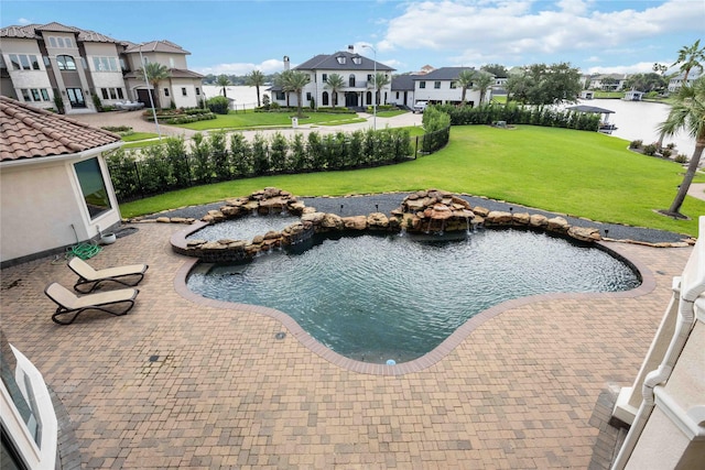 view of pool with fence, a lawn, a patio area, and a residential view