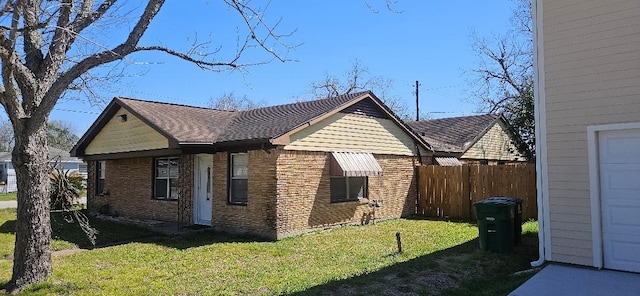 view of home's exterior featuring brick siding, a lawn, and fence