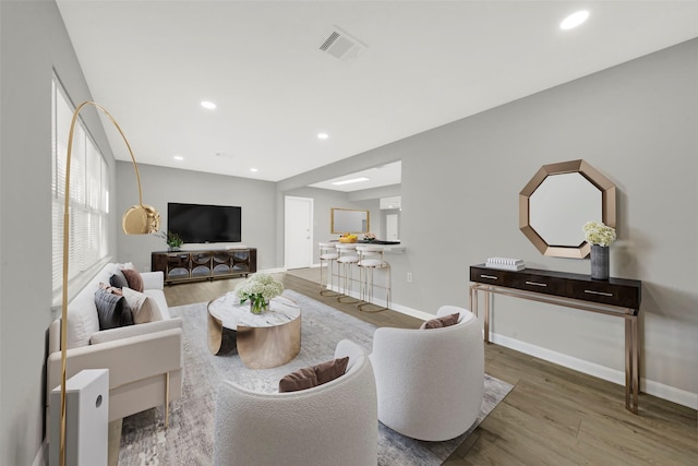 living area with recessed lighting, wood finished floors, visible vents, and baseboards