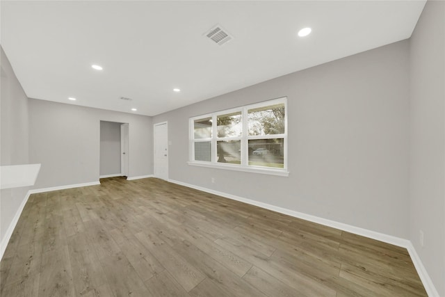 empty room with baseboards, visible vents, wood finished floors, and recessed lighting