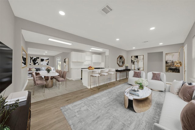 living area with light wood-style flooring, visible vents, and recessed lighting