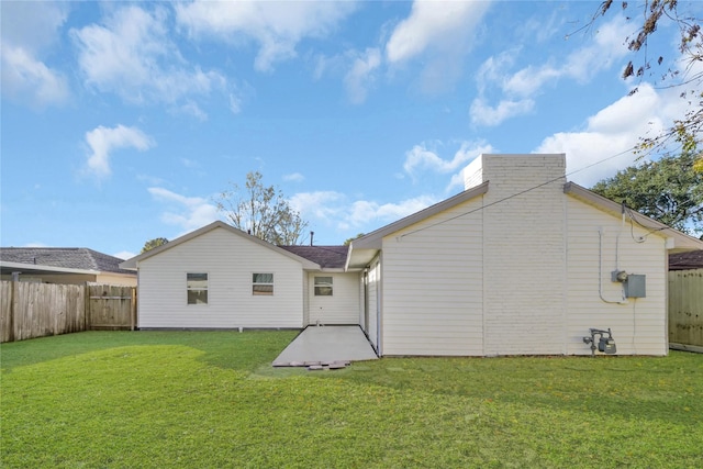 rear view of house featuring a fenced backyard and a lawn