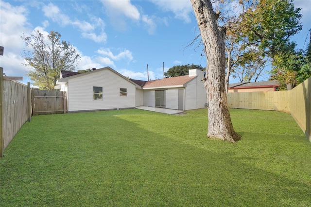 rear view of house with a yard, a patio, and a fenced backyard