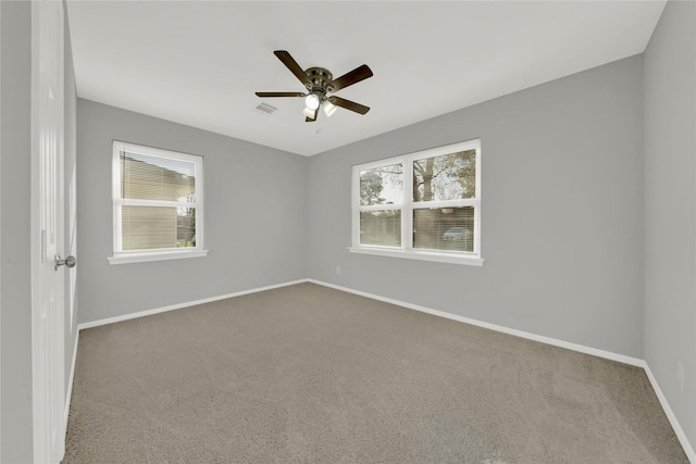 unfurnished room featuring carpet floors, visible vents, baseboards, and a wealth of natural light