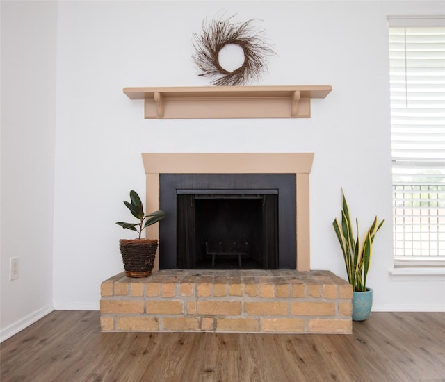 interior details featuring baseboards, a fireplace with raised hearth, and wood finished floors