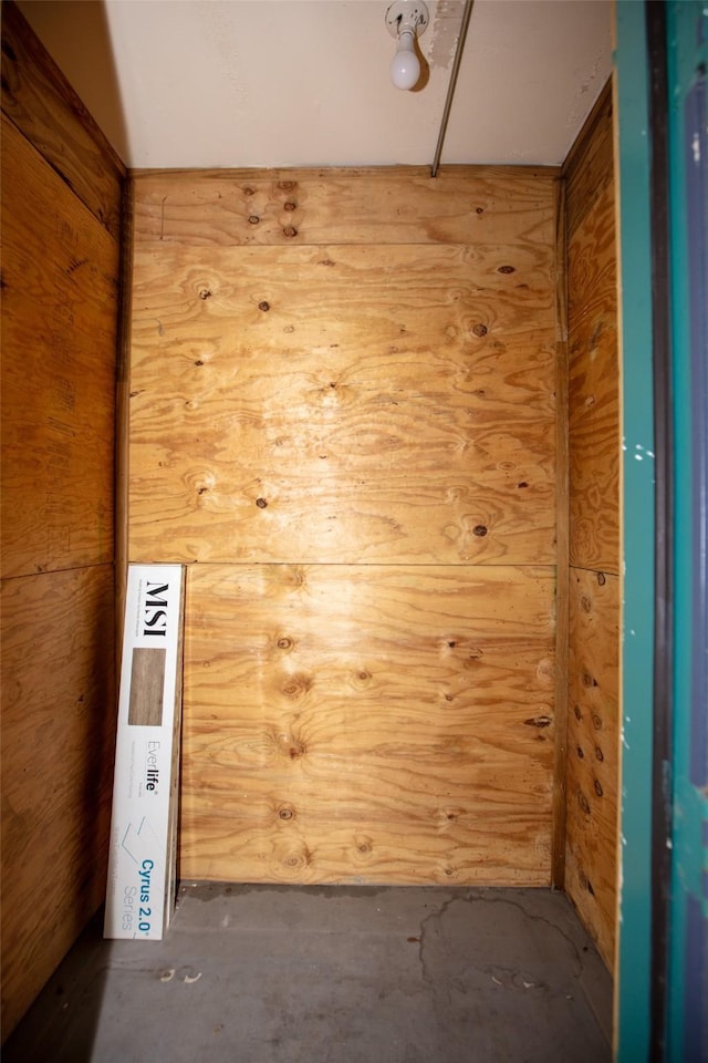 empty room featuring concrete floors and wooden walls