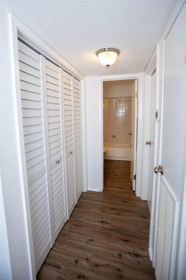 corridor featuring dark wood-style floors and a textured ceiling