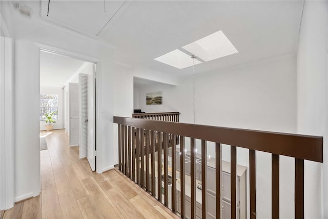 hallway with a skylight, visible vents, and wood finished floors