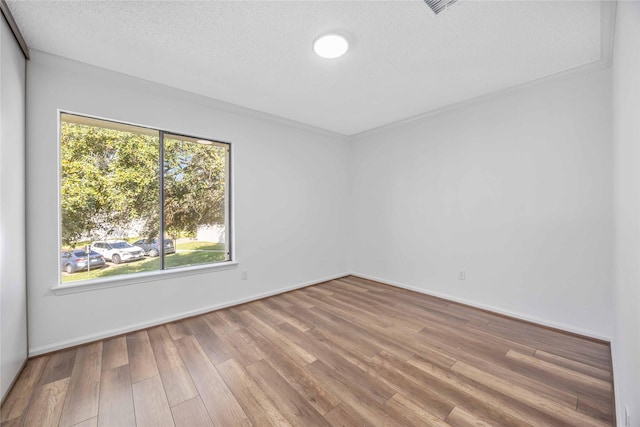 spare room with a textured ceiling, baseboards, and wood finished floors