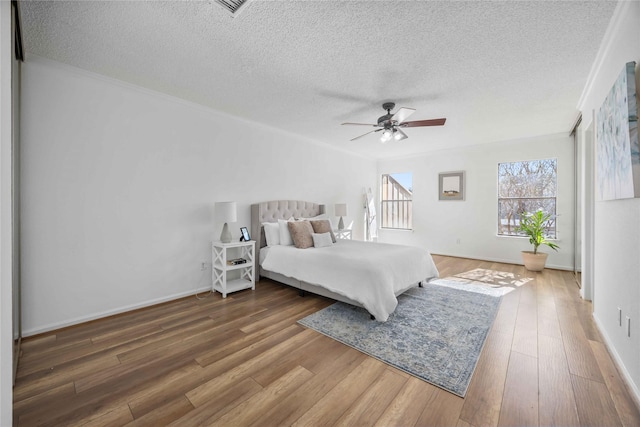 bedroom with a textured ceiling, wood finished floors, and baseboards