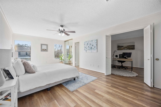 bedroom featuring a ceiling fan, light wood-style flooring, and a textured ceiling