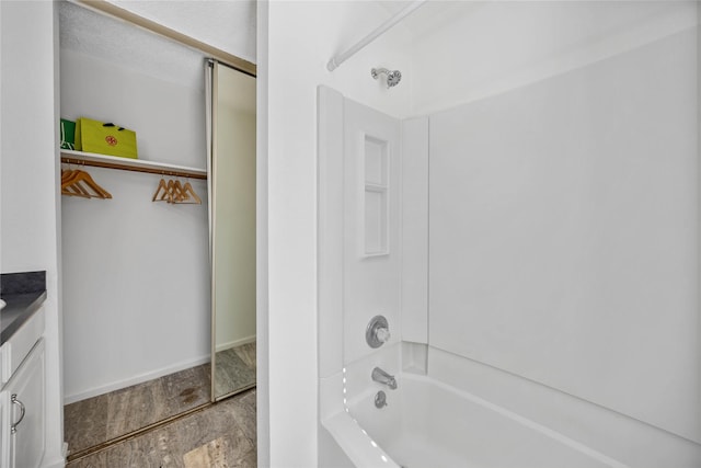 bathroom featuring  shower combination, baseboards, wood finished floors, and vanity