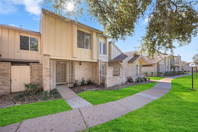 multi unit property featuring a front lawn, board and batten siding, and brick siding