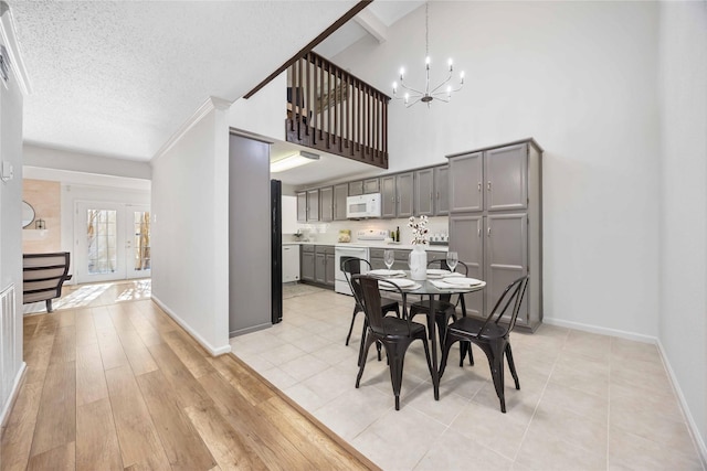 dining space with a chandelier, a textured ceiling, baseboards, french doors, and light wood-type flooring