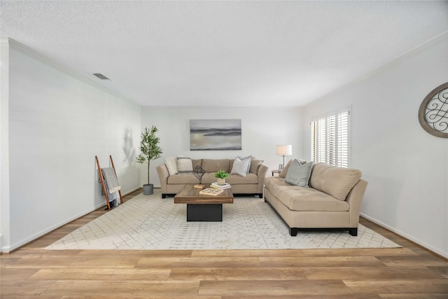 living room featuring baseboards, wood finished floors, visible vents, and crown molding