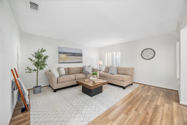 living area with crown molding, wood finished floors, visible vents, and baseboards