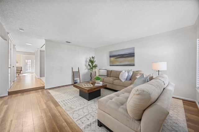 living room featuring baseboards, a textured ceiling, and hardwood / wood-style floors