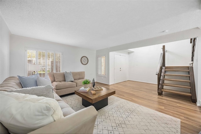 living area with wood finished floors, a textured ceiling, and stairs