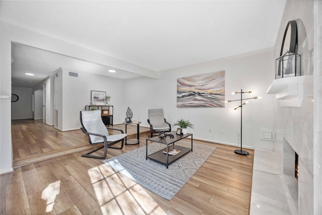 living area with wood-type flooring, visible vents, baseboards, and a premium fireplace