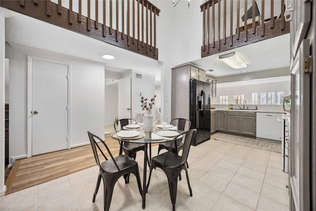 dining space featuring light tile patterned floors, a high ceiling, and visible vents